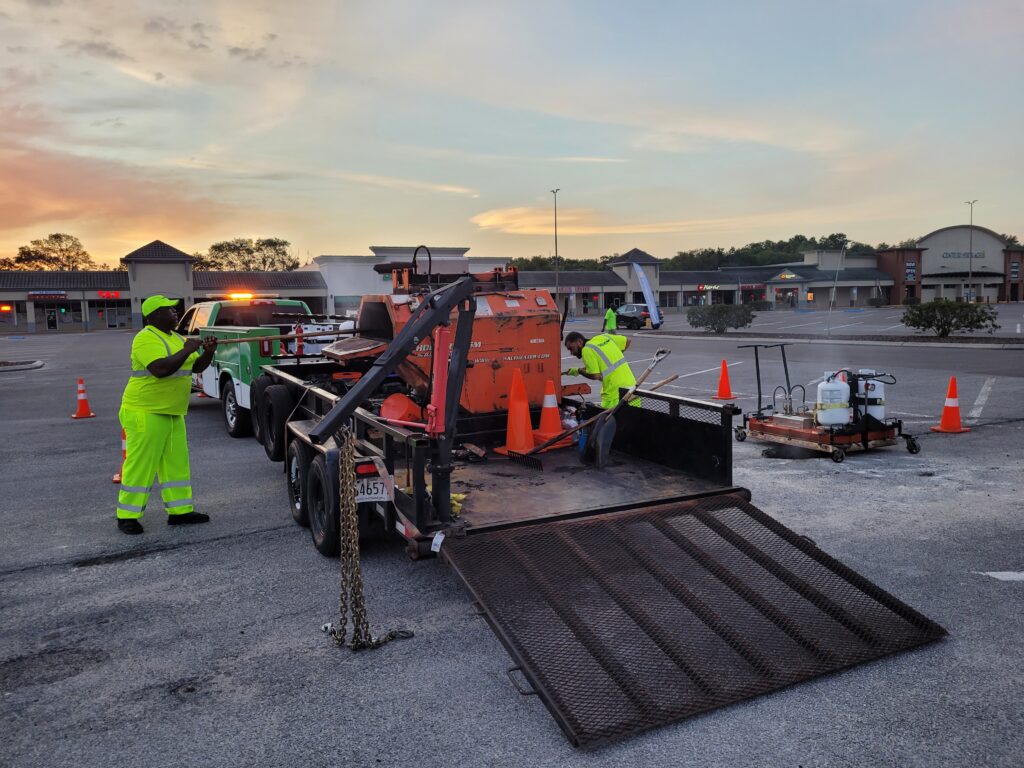 PotholeRepair.com crew and trailer-mounted thermal asphalt recycler set up inside a coned work zone in a commercial parking lot before business hours