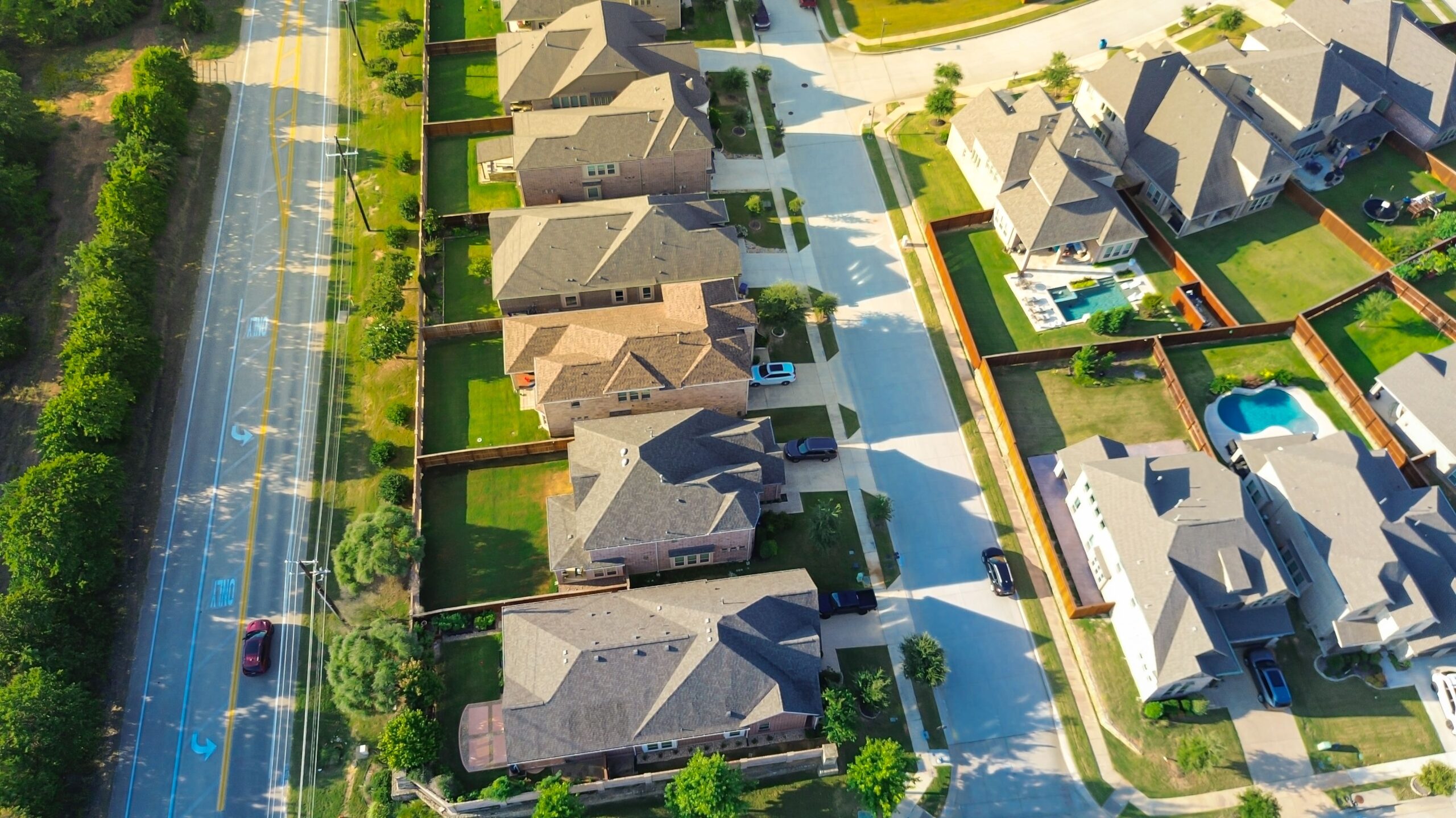 Aerial view of master-planned community featuring residential homes, neatly landscaped yards, and accessible roadways, emphasizing HOA-friendly design and maintenance.