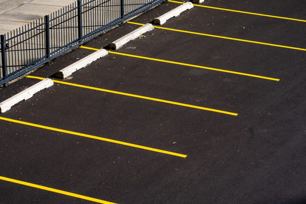 Empty commercial parking lot with fresh striping and wheel stops, the kind of property PotholeRepair.com assesses for pothole and asphalt repair before fall weather arrives
