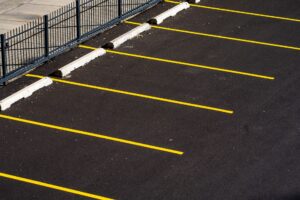 Empty commercial parking lot with fresh striping and wheel stops, the kind of property PotholeRepair.com assesses for pothole and asphalt repair before fall weather arrives