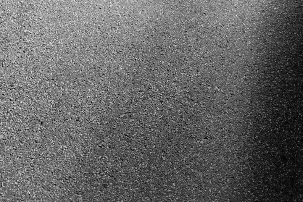 Close up of a commercial asphalt surface showing coarse aggregate texture and early surface wear