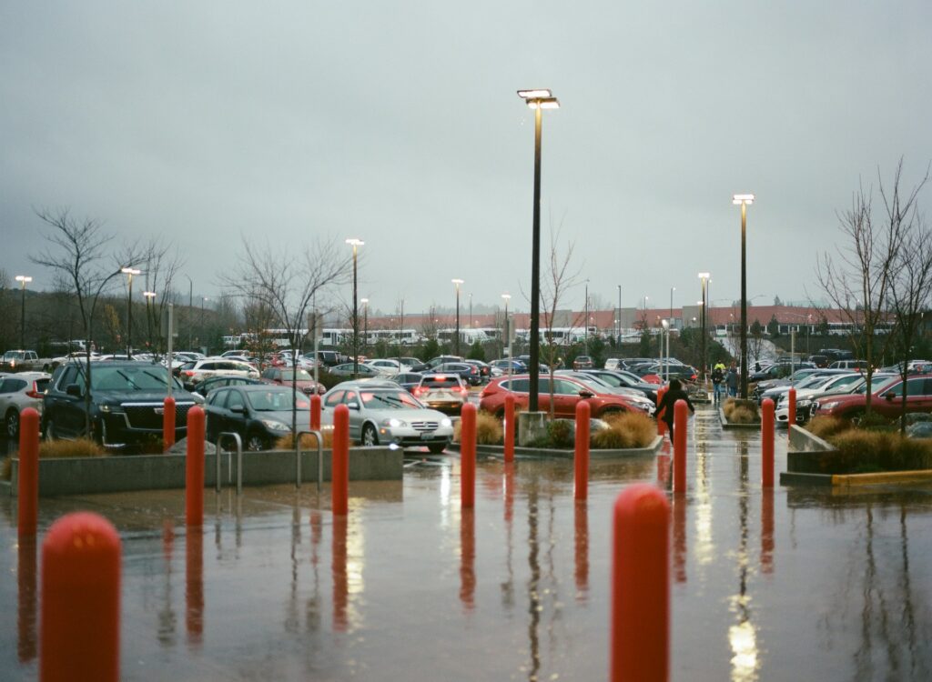 Rain-soaked commercial retail parking lot after a major storm, standing water pooling across the asphalt drive lanes